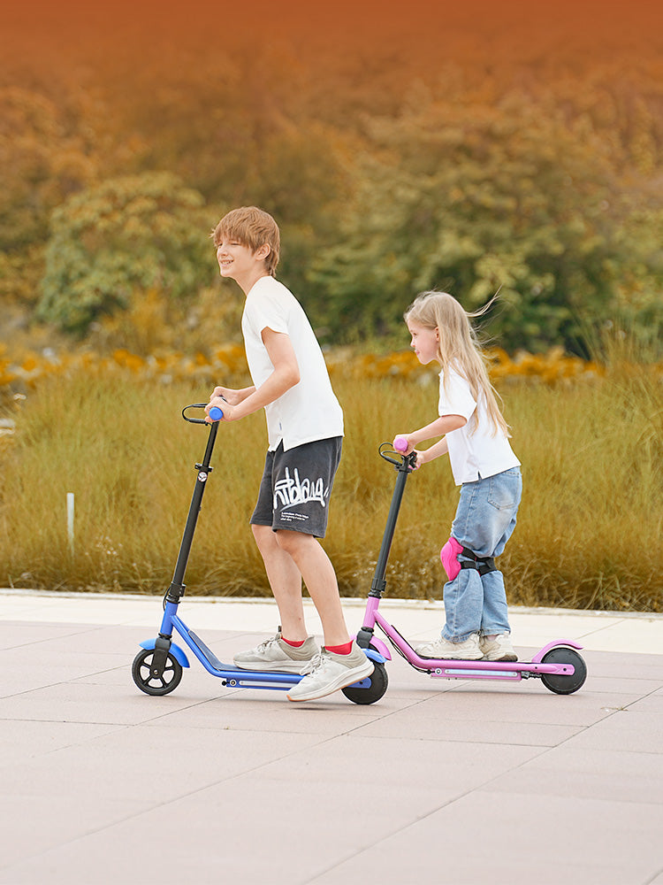 Action shot of a boy and girl enjoying a outdoor ride together on colorful iScooter IK3Pro electric scooters designed for children. Featuring height-adjustable handlebars to accommodate growing kids, secure responsive braking, reliable smooth-rolling wheels, and a lightweight frame, this kid-friendly e-scooter brings active play and effortless handling to every adventure.