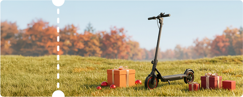 Wide landscape-style product image showing a sleek black iScooter W5 electric scooter parked on a sunny lawn surrounded by holiday presents against a soft background of autumn foliage. Engineered for reliable daily commutes, this compact e-scooter features solid air-filled tires, subtle red rim highlights, dual rear shock absorption, a kickstand, and a quick-fold stem for easy carrying and storage.