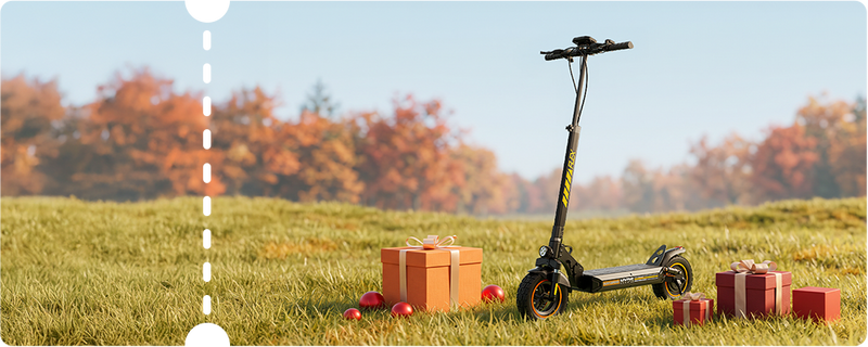 Bright, sunlit outdoor view highlighting a black iScooter W9 Air electric scooter standing in an open grassy field decorated with holiday present packages and autumn trees. Built for smooth long-range travel, this advanced e-scooter showcases vibrant yellow stem decals, high-grip pneumatic tires with orange accents, heavy-duty shock absorption, an integrated LED headlight, and a spacious non-slip foot deck for supreme stability and comfort.